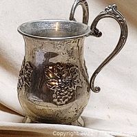 Full view of silver chalice showing one handle and grapevine decoration.