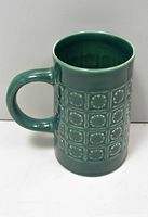 Full side view showing handle and embossed design on ceramic mug.