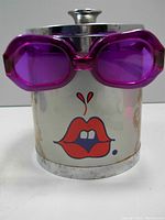 Front view of ice bucket showing lips pop art graphic and pink sunglasses handle attached to lid side.