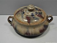 Front angled view of vintage artisan lidded pottery dish showing handles and lid knob