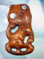 Front view of the hand carved wooden Hei Tiki talisman showing detailed carving and abalone paua shell eyes.