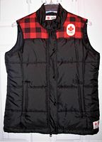 Front view of black insulated vest with red plaid shoulders and Canada Olympic patch