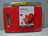 Front view of packaged set showing red cutting board, label with tomatoes and knife handle contained inside clear plastic.