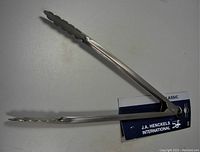 J.A. Henckels stainless steel locking kitchen tongs with scalloped gripping edges, showing side view and locking mechanism.