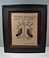 Front view of framed needlework showing embroidered quote, birds, and signature.