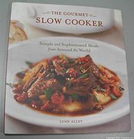 Front cover of 'The Gourmet Slow Cooker' cookbook by Lynn Alley showing plated cooked food and title text.