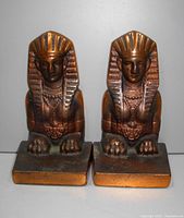 Front view of pair of Egyptian Revival sphinx metal bookends on a white background.