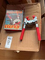 Bottle capper gadget with red handles and original box labeled 'tappatrice per tappi corona eterna'
