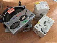 Shows the assembled lot with frying pans stacked and meat grinders boxed on a wooden floor.