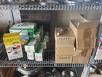 Overview of shelf with boxes containing potato press, gnocchi maker, packaged herb graters, pizza cutters, and garden snippers.
