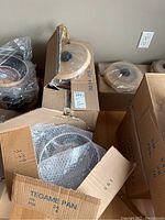 Multiple cardboard boxes containing new Teflon coated pans and lids, still in packaging.