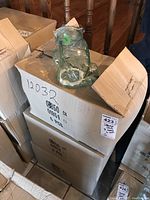 Photo showing boxes of pressed glass car motif storage jars with one jar displayed on top, highlighting the overall shape and packaging.