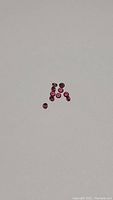 Ten loose round faceted rubies arranged loosely on neutral background