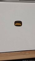 Photo of a cushion cut natural golden citrine gemstone with a rich golden-yellow tone laid on a white background.