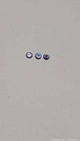 Three round natural tanzanite gemstones displayed on neutral background, showing deep blue and purple hues, faceted with diamond cut style to enhance brilliance.