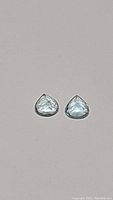 Close-up of two pear-shaped aquamarine gemstones showing their color and cut details.