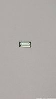 Front view of the rectangular baguette cut bright yellow tourmaline gemstone on a grey background