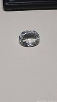 Top view of large faceted oval natural clear crystal quartz on neutral background