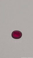 Close-up of the oval cut ruby showing rich blood red color and facets.
