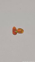 Two untreated natural Ethiopian chocolate opals on plain white background showing orange and green flashes