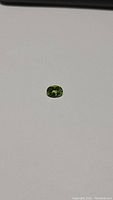 Top view of the oval Peridot showing bright apple green color and faceting details.