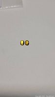 Pair of oval-shaped sapphires showing strong yellow color gradients with hints of blue, laid flat on white background.
