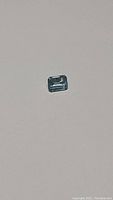 Horizontal close-up of rectangular emerald cut soft blue aquamarine gemstone on plain background.