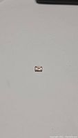 Photo of 1.04 ct peach tourmaline gemstone from a distance showing its rectangular emerald cut shape and peach color.