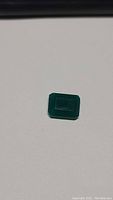 Photo showing a shining vivid green onyx gemstone cut in emerald shape on white background