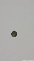 Photo of single round diamond cut olive green natural tourmaline gemstone on a plain background