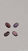 Top-down view of four oval cut sapphires in various rare colors including purple, pink, pink-orange and padparadscha.