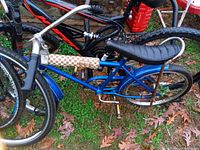 Side view of a vintage blue bicycle with a black banana seat, showing the entire frame, wheels, and handlebars.