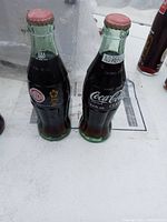 Two vintage Coca-Cola glass bottles with Bicentennial-themed labels and original caps, shown on a white surface.