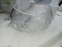 Clear crystal bowl viewed from side angle showing etched floral pattern and round shape.
