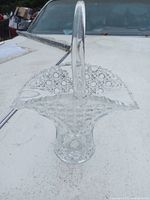 Top angle photo of clear glass basket showing handle, patterned sides and rounded base.