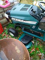Front-left angle view showing green engine cover with ULTRA decal, U.S. Army star sticker, front tire and mower deck