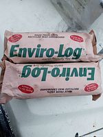 Two wrapped Enviro-Log fire logs made from recycled wax cardboard lying on white surface.