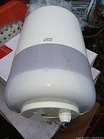 Photo showing white Tork brand towel dispenser with translucent cover and dispenser knob.