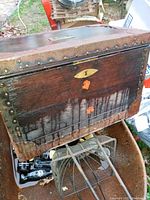 Front and side view of a small wooden chest showing rusted metal rivets and peels on wood surface