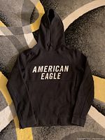 Front view of black American Eagle hoodie with 'AMERICAN EAGLE' print on chest