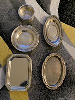 Image showing the full set of four plates and one bowl on a carpeted floor; visible scratches and marks on all pieces