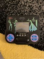 Front view of the handheld electronic game featuring Batman Forever themed artwork, control buttons, and screen.