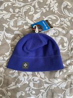 Top side view of the brand new Columbia purple fleece beanie hat showing logo patch and attached tag.