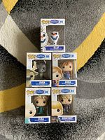 Photo showing all five boxed Disney Frozen Funko Pop figures arranged on carpet - Olaf, Sven, Anna, Elsa, Kristoff