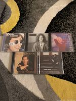 Front covers of five CD jewel cases on a carpet background, showing the featured artists and album titles.