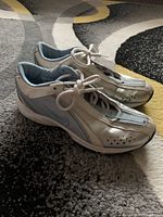 Left side angled view of white Nike women's sneakers with light blue accents showing shape, condition, and laces tied.