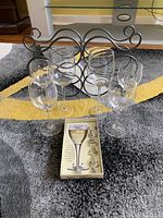 Overview photo showing 4 clear wine glasses, 2 with spiral stems, with a silver metal bottle holder behind them and a box of wine glass markers in front.
