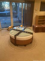 Front view of circular glass coffee table with four stools tucked under