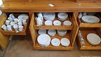 Photo showing the cabinets opened with all china pieces organized inside: cups, plates, bowls, platters, tea pots and pitchers.