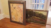 Pair of framed paintings side by side on a hardwood floor, showing overall size and framing style
